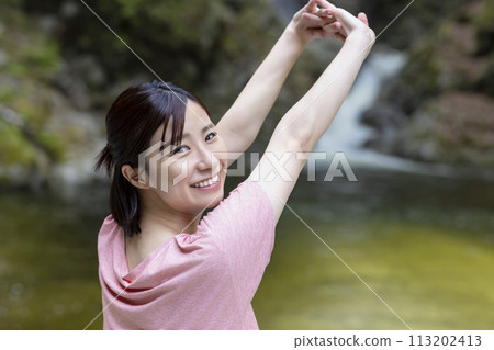 A refreshing woman stretching in the forest 113202413