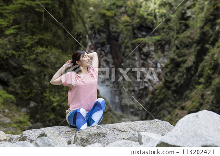 A refreshing woman stretching in the forest 113202421