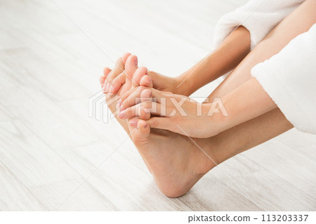 A woman massaging the soles of her feet. 113203337