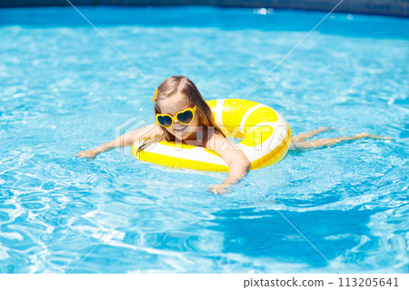Child in swimming pool on ring toy. Kids swim. 113205641