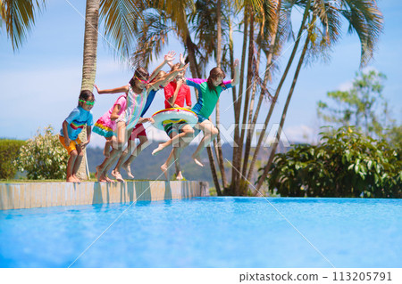 Kids jump into swimming pool. Summer water fun. 113205791