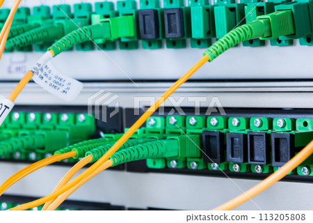 fiber optic cables plugged in network switch panel inside data center 113205808