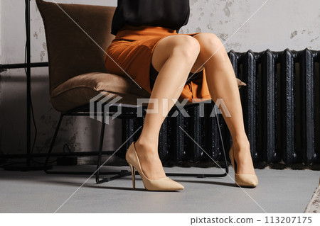 Unrecognizable woman sitting in a chair with her knees closed 113207175