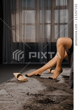 Female legs in stockings with a belt on the carpet 113207191