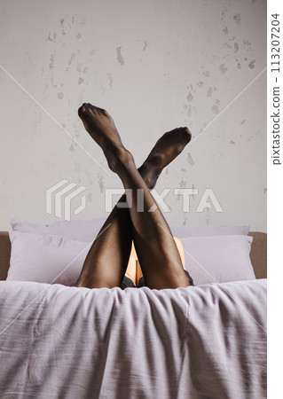 Low angle view at female legs in stockings on bed 113207204