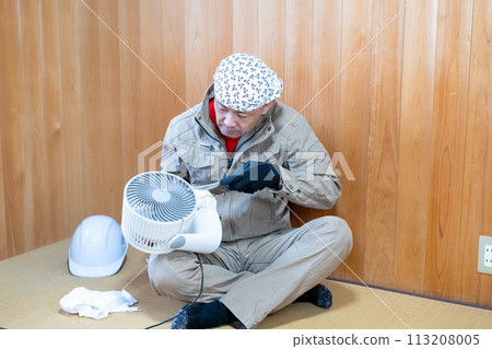 A man on his way home from work disassembling and cleaning an air circulator in preparation for the hot season A man on his way home from work disassembling and cleaning an air circulator in preparation for the hot season 113208005