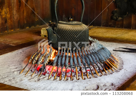 Fresh fish (Iwana) cooking over a wooden fire in a Japanese mountain hut Fresh fish (Iwana) cooking over a wooden fire in a Japanese mountain hut 113208068