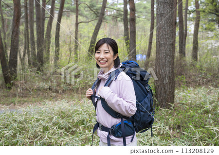 A woman enjoying a hike in fresh greenery A woman enjoying a hike in fresh greenery 113208129
