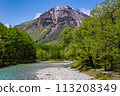Fast flowing clear river running through a forest and mountains 113208349
