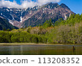 Shallow lake in front of forest and towering snow covered peaks (Hotaka Range, Kamikochi, Japan) 113208352