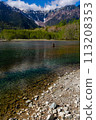 Shallow lake in front of forest and towering snow covered peaks (Hotaka Range, Kamikochi, Japan) 113208353