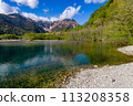 Lake and forest in front of towering, snow-capped mountains with a blue sky 113208358