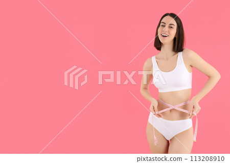 A slim girl in underwear measures her waist. 113208910