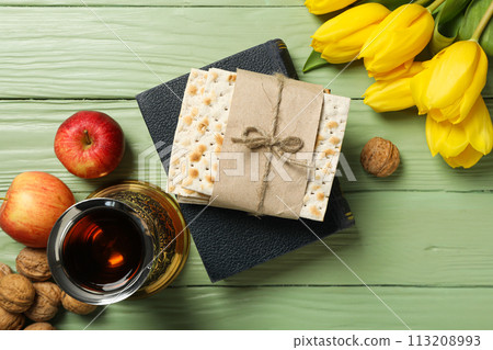 Matzo on the Torah, cup, apples and flowers on green wooden background, top view 113208993