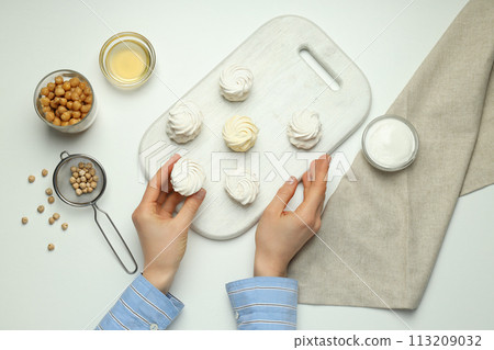Marshmallows on board in hands, towel and bowls with chickpeas and cream on white background, top view Marshmallows on board in hands, towel and bowls with chickpeas and cream on white background, top view 113209032