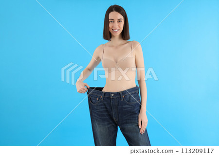 Slender girl in large pants, on a blue background. 113209117