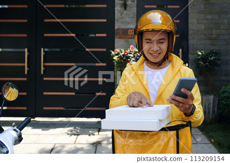 Courier checking address of customer on pizza box Courier checking address of customer on pizza box 113209154