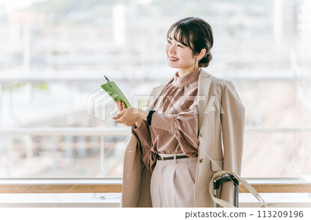 A businesswoman/young woman checking the time on her watch while looking at her schedule book 113209196