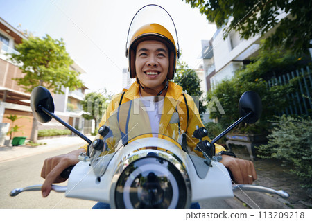 Excited Vietnamese young man riding motorbike delivering food to customers 113209218