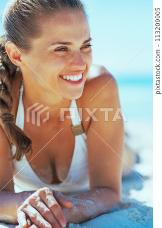 Happy young woman laying on beach and looking on copy space Happy young woman laying on beach and looking on copy space 113209905