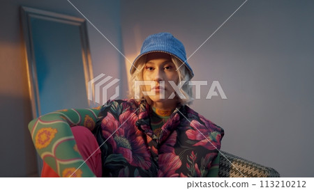 Cool hipster student woman wearing stylish outfit looking at camera and correcting her hat Cool hipster student woman wearing stylish outfit looking at camera and correcting her hat 113210212