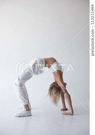 Beautiful blonde girl in a white top and tights posing on a white background 113211464