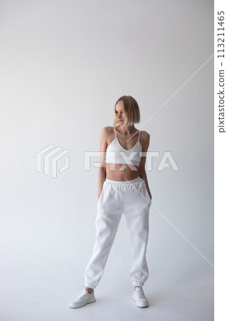 Beautiful blonde girl in a white top and tights posing on a white background 113211465