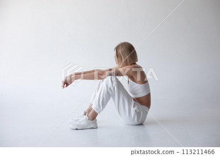 Beautiful blonde girl in a white top and tights posing on a white background 113211466