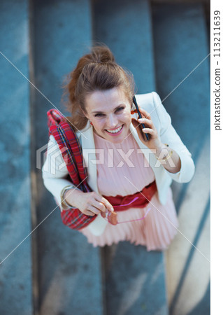 happy stylish 40 years old woman in city speaking on smartphone 113211639