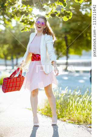 happy elegant female in pink dress and white jacket in city happy elegant female in pink dress and white jacket in city 113211642