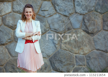 happy modern woman in pink dress and white jacket in city 113211654