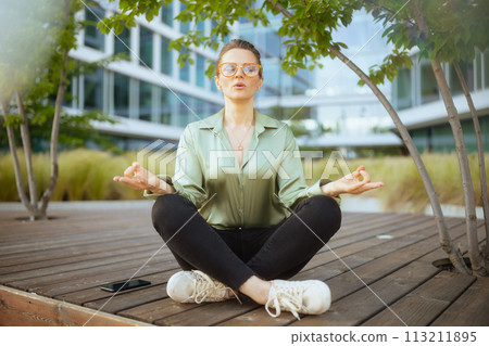business woman in green blouse and eyeglasses meditating 113211895