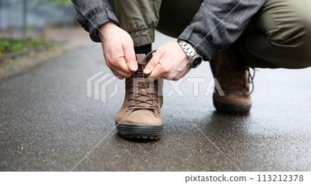 Male hand tie shoelaces on brown shoes closeup Male hand tie shoelaces on brown shoes closeup 113212378