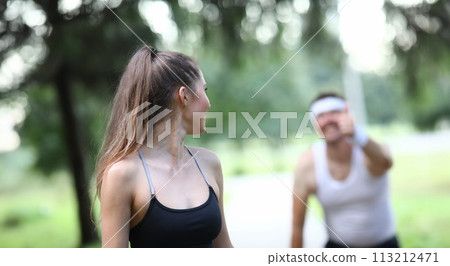 Slender girl looks back at man showing ok gesture. 113212471