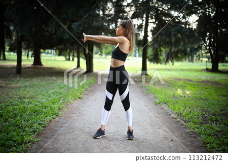 Sporty girl is doing exercises in park to warm up. 113212472