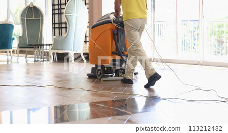 Cleaner washing floor of hotel lobby with machine closeup 113212482