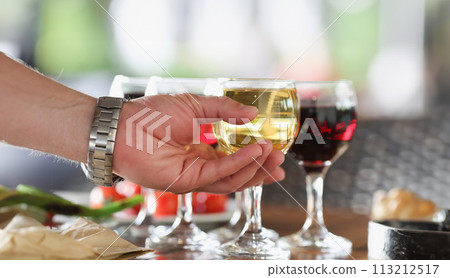 Man hand taking glass of white wine in restaurant closeup 113212517