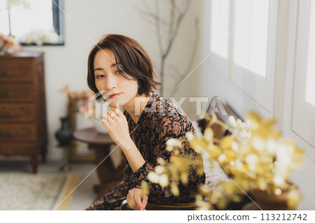中年婦女坐在房間的沙發上 中年婦女坐在房間的沙發上 113212742