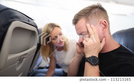 Young man is flying in airplane and holding sore head 113213165