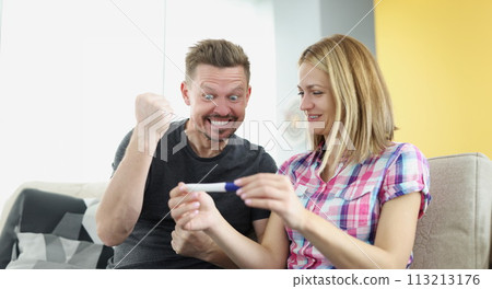 Man and woman rejoicing and holding positive pregnancy test at home 113213176