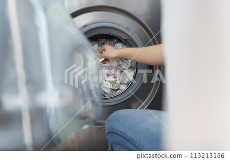 Woman pulling out clean clothes from washing machine in bathroom closeup 113213186