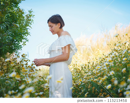 Beautiful Asian young woman in white dress outdoor in flower field. embracing fresh air and engaging in outdoor activities. Friluftsliv concept means spending as much time outdoors as possible 113213458