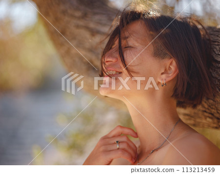 Beautiful Asian young woman in white dress outdoor near olive tree. embracing fresh air and engaging in outdoor activities. Friluftsliv concept means spending as much time outdoors as possible 113213459