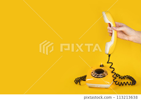 Banner with old yellow phone, hand picks up the phone on yellow background flat lay copy space Banner with old yellow phone, hand picks up the phone on yellow background flat lay copy space 113213638