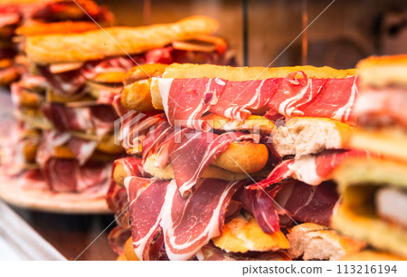 Delicious ham hanging from sandwiches in a store window Delicious ham hanging from sandwiches in a store window 113216194