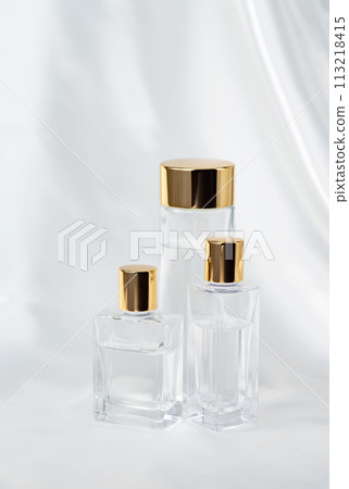 Clear glass cosmetic bottles and satin white cloth 113218415