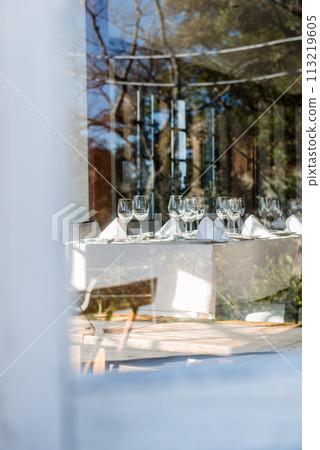 Wine glass and table setting, photographed through the glass window 113219605