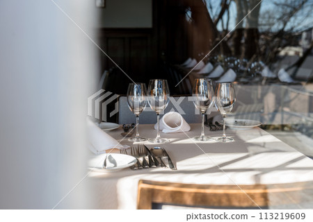 Wine glass and table setting, photographed through the glass window 113219609