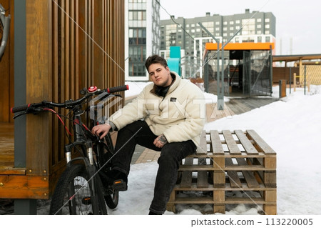 Lifestyle concept, young man sitting at a bus stop with a bicycle Lifestyle concept, young man sitting at a bus stop with a bicycle 113220005