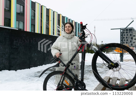 Woman Standing Next to Bike in the Snow 113220008